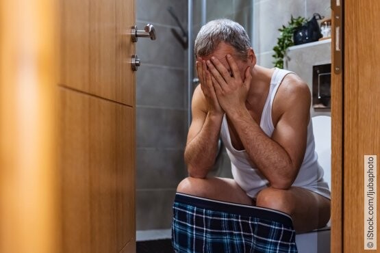 Mann auf Toilette mit sichtlichen Schmerzen